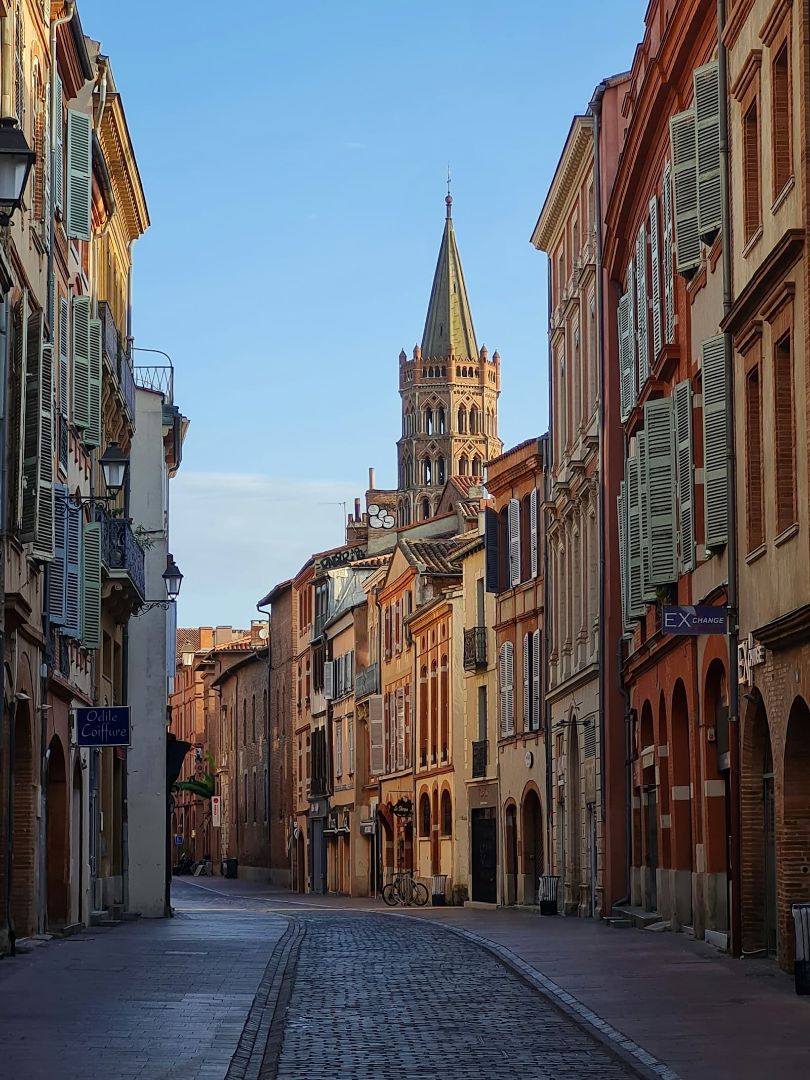 Une rue de brique rose de Toulouse et le clocher de Saint-Sernin